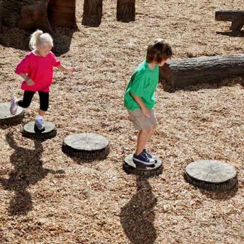 Circular pieces of wood on the ground that kids are hopping to and from on.