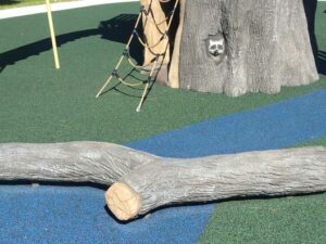A large realistic looking branch provides a balance challenge on a playground