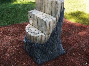 Deck access climber in the shape of a chopped log with chopped in steps and brown bark