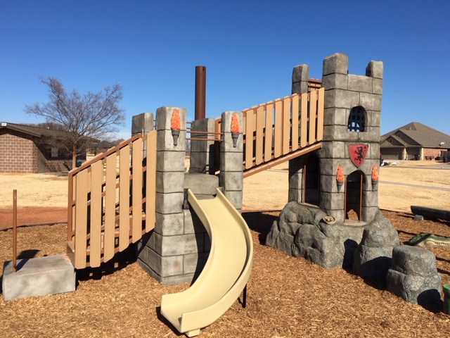 Castle themed playground structure on top of rocks w/climbers
